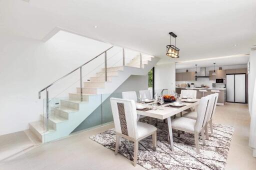 Modern dining area next to staircase with view of the kitchen