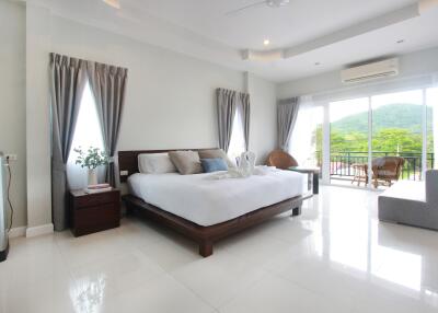 Spacious bedroom with a large bed, balcony view, and ample natural light