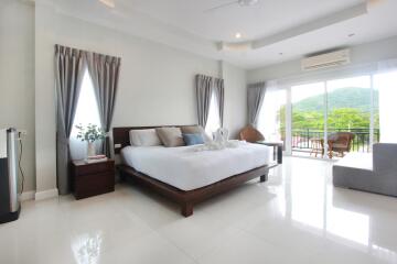 Spacious bedroom with a large bed, balcony view, and ample natural light