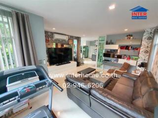 Modern living room with a large TV, comfortable seating, exercise equipment, and stylish decor