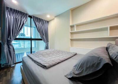 Well-lit modern bedroom with a bed, pillows, and large window