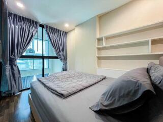 Well-lit modern bedroom with a bed, pillows, and large window