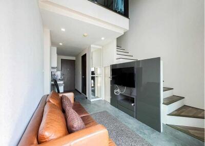 Modern living room with leather sofa, TV, open kitchen and stairs