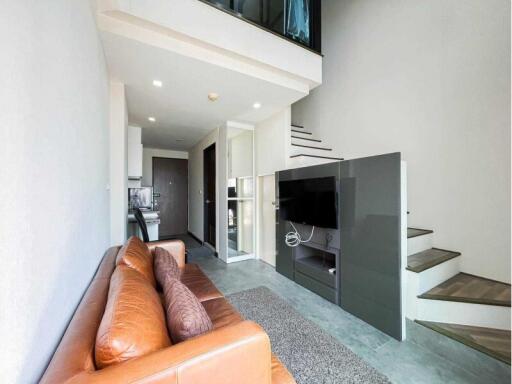 Modern living room with leather sofa, TV, open kitchen and stairs