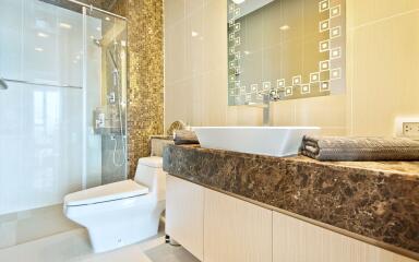 Modern bathroom with glass shower, toilet, and stylish sink