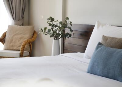 Cozy bedroom with a wicker chair, decorative pillows, and a plant