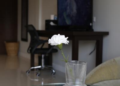 Modern living room with a work desk and a single white flower in a vase