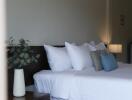 Bedroom with neatly arranged pillows and a bedside table with a vase