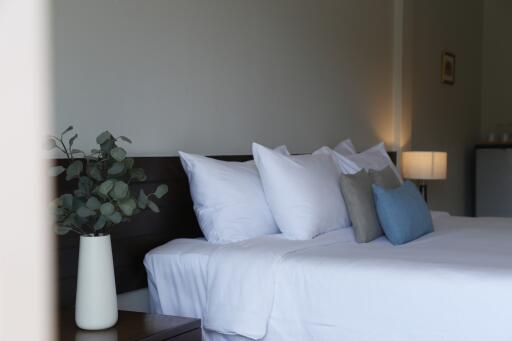 Bedroom with neatly arranged pillows and a bedside table with a vase