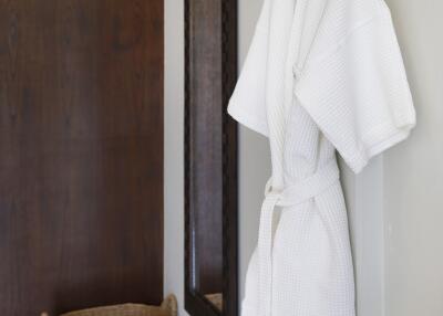 Bathroom with a hanging white robe, woven basket, and large mirror