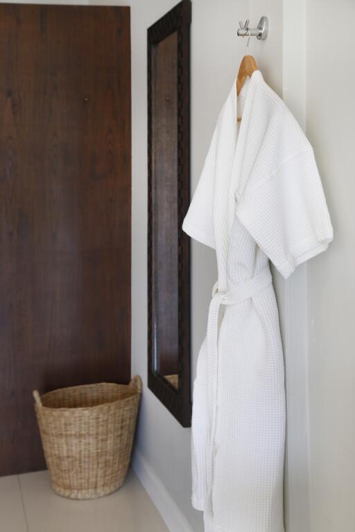 Bathroom with a hanging white robe, woven basket, and large mirror