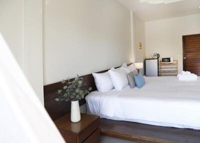 well-lit modern bedroom with white bedding and wooden accents