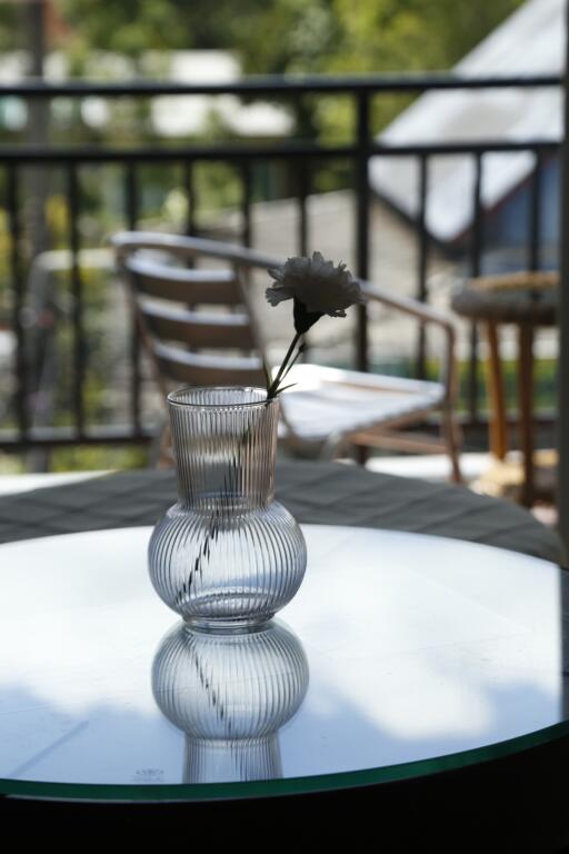 Glass vase with flower on table on balcony