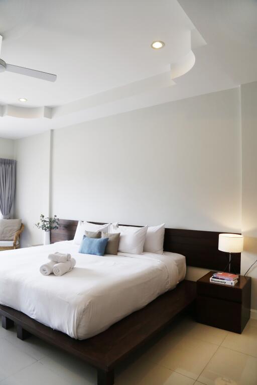 Modern well-lit bedroom with bed, pillows, side table, and lamp