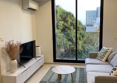 A cozy living room with a sofa, coffee table, TV, and large window.