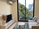 A cozy living room with a sofa, coffee table, TV, and large window.