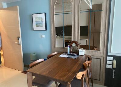 Dining area with a wooden table and chairs, wall mirror, and adjoining kitchen
