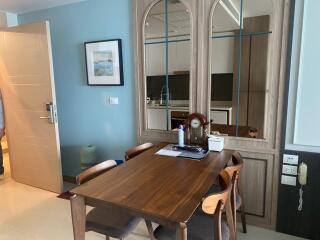 Dining area with a wooden table and chairs, wall mirror, and adjoining kitchen