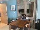Dining area with a wooden table and chairs, wall mirror, and adjoining kitchen