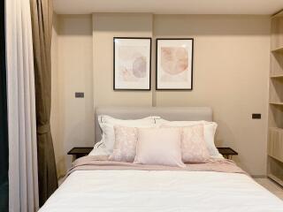 Cozy bedroom with double bed, decorative pillows, and framed art above the headboard.