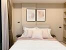 Cozy bedroom with double bed, decorative pillows, and framed art above the headboard.