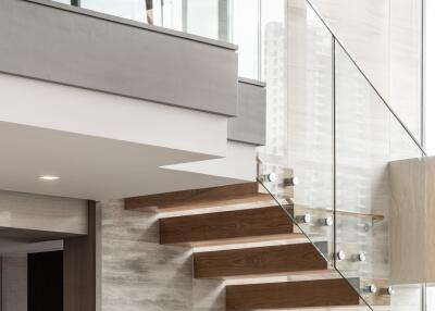 Modern interior with floating wooden staircase and glass railings
