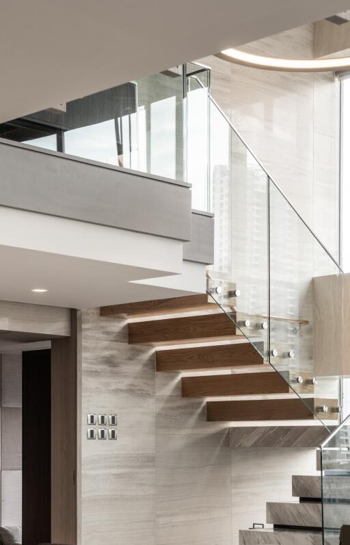 Modern interior with floating wooden staircase and glass railings