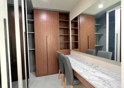 Modern walk-in closet with built-in wooden cabinetry and marble-topped vanity