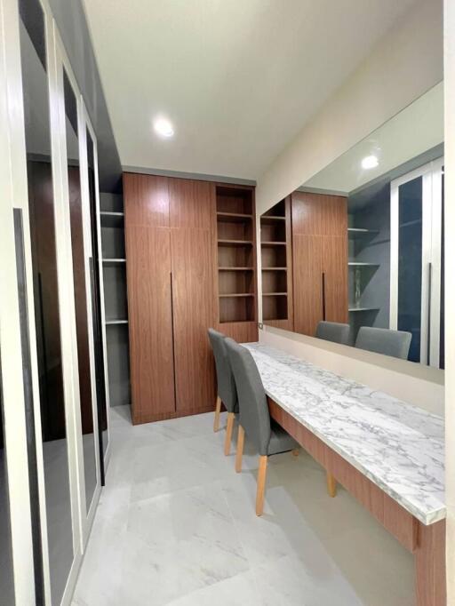 Modern walk-in closet with built-in wooden cabinetry and marble-topped vanity