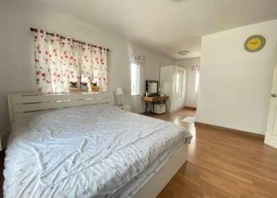 Spacious and bright bedroom with double bed and floral curtains