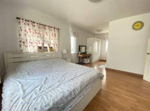 Spacious and bright bedroom with double bed and floral curtains