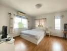 Bright bedroom with wooden floors and white furniture