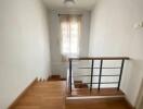 Staircase with wooden steps and handrail leading to hallway with window