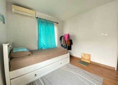 Bedroom with single bed, window with turquoise curtains, and air conditioning