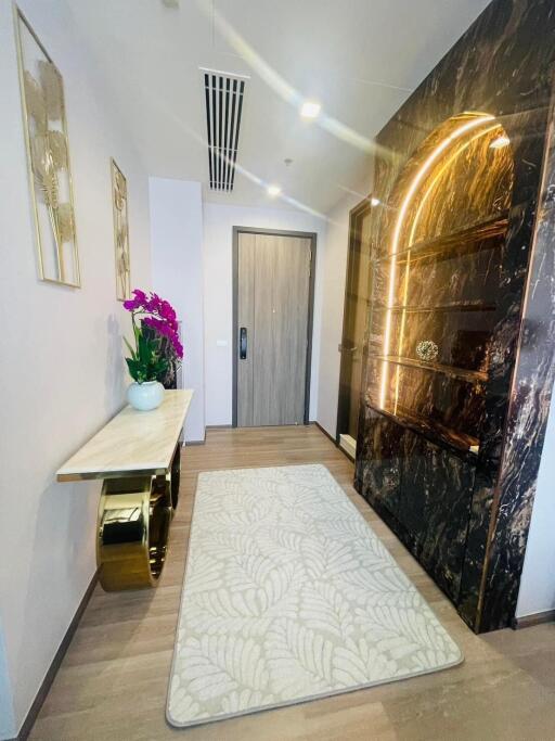 Modern hallway with a decorative console table, luxurious shelving, and a door