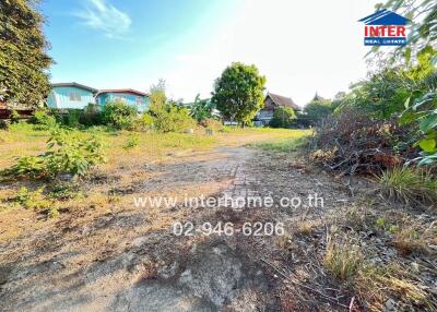 Vacant plot of land with some greenery and distant houses