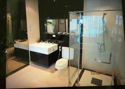 Modern bathroom with glass shower, large sink, and toilet