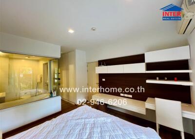 Modern bedroom with a large window, en-suite bathroom, desk area, and air conditioning