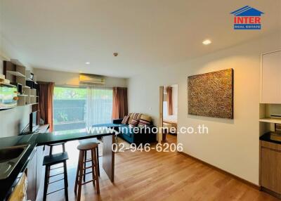 Modern living room and kitchen area with wooden flooring and large window