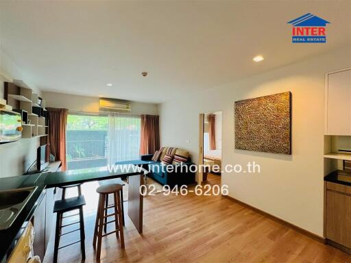 Modern living room and kitchen area with wooden flooring and large window