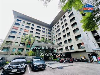 Exterior view of a multi-story apartment building with parking area