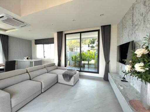 Modern living room with gray sectional sofa, large window, and television