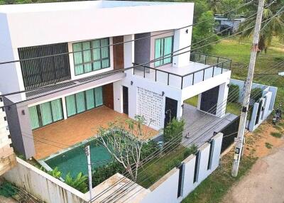 Modern two-story house with a pool and green surroundings