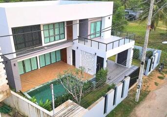 Modern two-story house with a pool and green surroundings