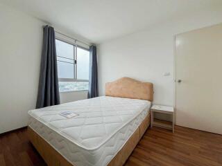 A simple bedroom with a bed, nightstand, and window with curtains