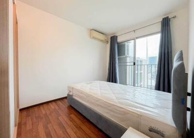 Spacious bedroom with a large bed, wooden flooring, air conditioning, and a window with curtains.