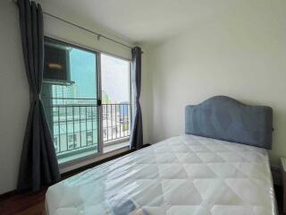 Bedroom with a bed next to a window and balcony