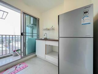 Compact kitchen area with adjacent balcony and fridge