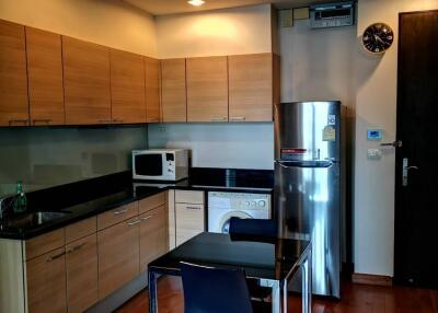 Modern kitchen with wooden cabinets, stainless steel appliances, and a small dining area