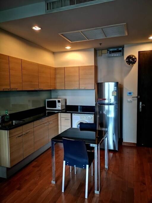 Modern kitchen with wooden cabinets, stainless steel appliances, and a small dining area